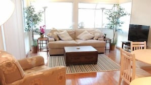 A living room with a sofa, armchair, coffee table, and TV. - Lake Arrowhead Pad (Myrtle Beach)
