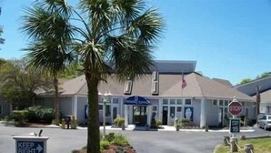 A hotel entrance with a palm tree, a stop sign, and a 'Keep Right' sign. - Lake Arrowhead Turf (Myrtle Beach)