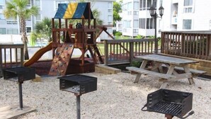 A playground with a slide and climbing wall, surrounded by a wooden deck and picnic table. - Lake Arrowhead Break (Myrtle Beach)
