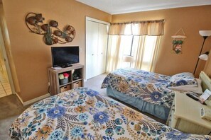 Ein Schlafzimmer mit zwei Betten, einem Fernseher und einem Fenster mit Vorhängen.
