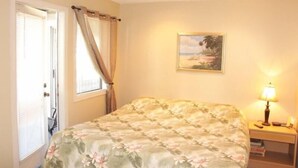 A bedroom with a bed, a window with curtains, a bedside lamp, and a painting on the wall. - Lake Arrowhead Layaway (Myrtle Beach)