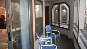 Un porche cubierto con dos sillas azules y una puerta de vidrio que da a una habitación.
