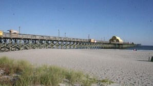 Un muelle que se adentra en el agua, con un edificio al final.