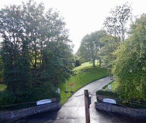 A paved pathway leading through a park with a stone wall on one side and a grassy hill on the other. - Abinger Guest House (Leicester)