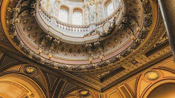 An ornate interior with a large circular dome, columns, and classical statues.