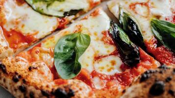 A pizza with cheese, tomato sauce, and basil leaves on a plate.