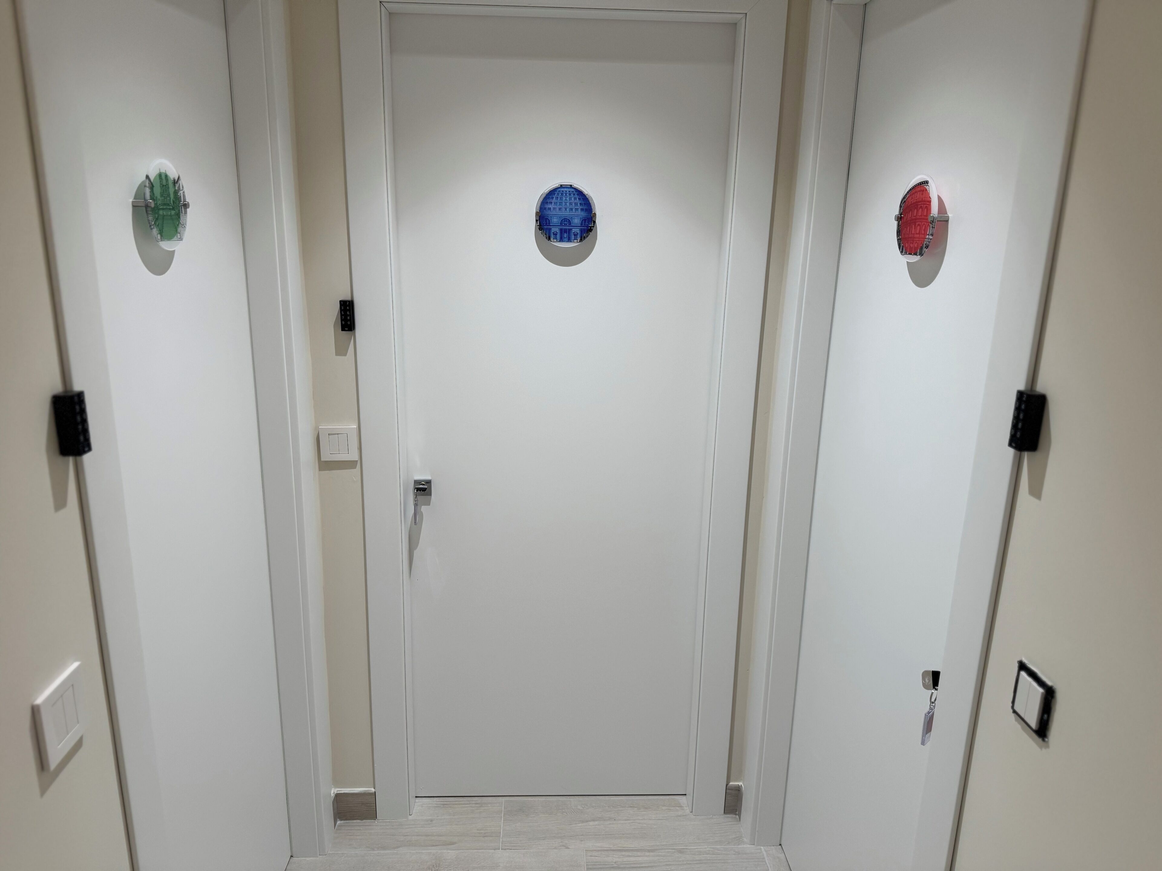 Un pasillo con tres puertas, cada una con una placa decorativa distintiva encima.