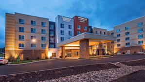 Ein mehrstöckiges Hotel mit Fairfield Inn & Suites und Towneplace Suites Schildern, mit überdachter Eingangspartei und Parkplatz.