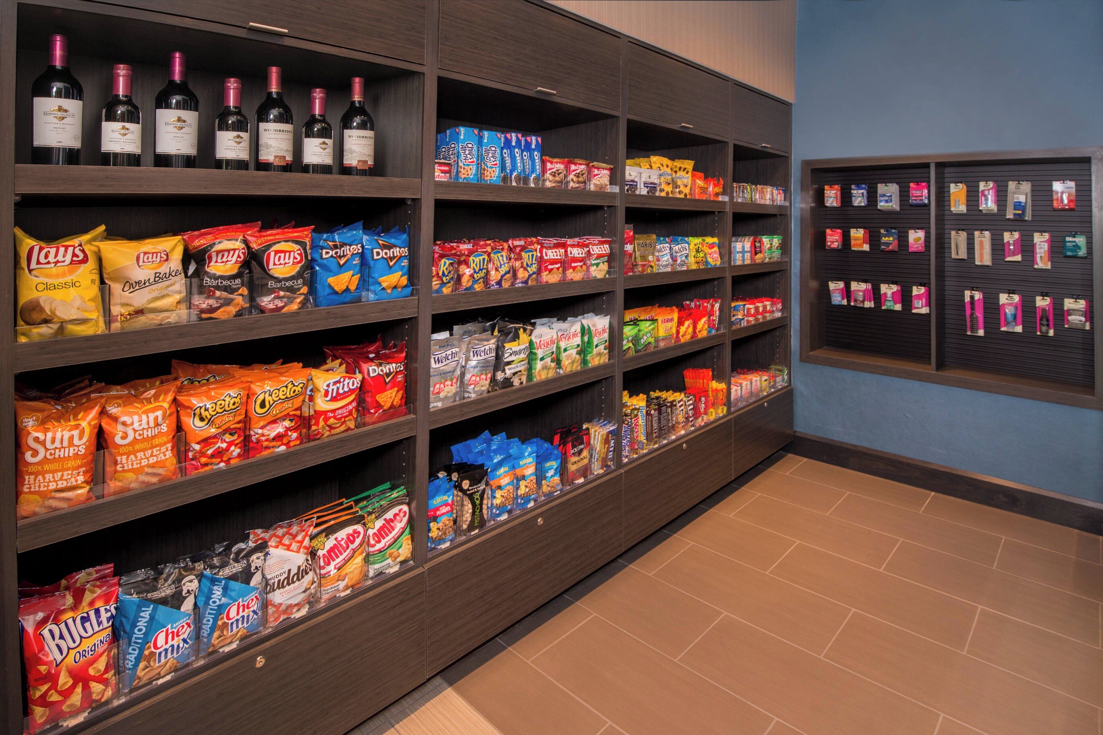 Een schap met verschillende chips en snacks, met daarboven een wijnsectie.
