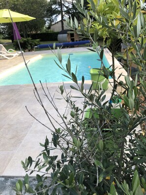 A swimming pool with a tiled deck, surrounded by greenery and a yellow umbrella. - Les Plantous de Severo (Cenac-et-Saint-Julien)
