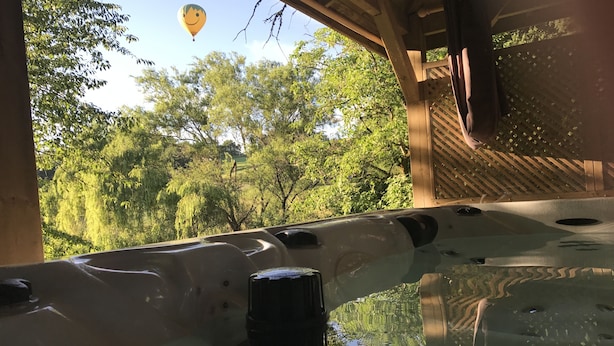 A hot tub with a view of trees and a hot air balloon in the background. - Les Plantous de Severo (Cenac-et-Saint-Julien)