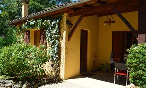 A yellow building with a wooden porch, a door, and a window. - Les Plantous de Severo (Cenac-et-Saint-Julien)