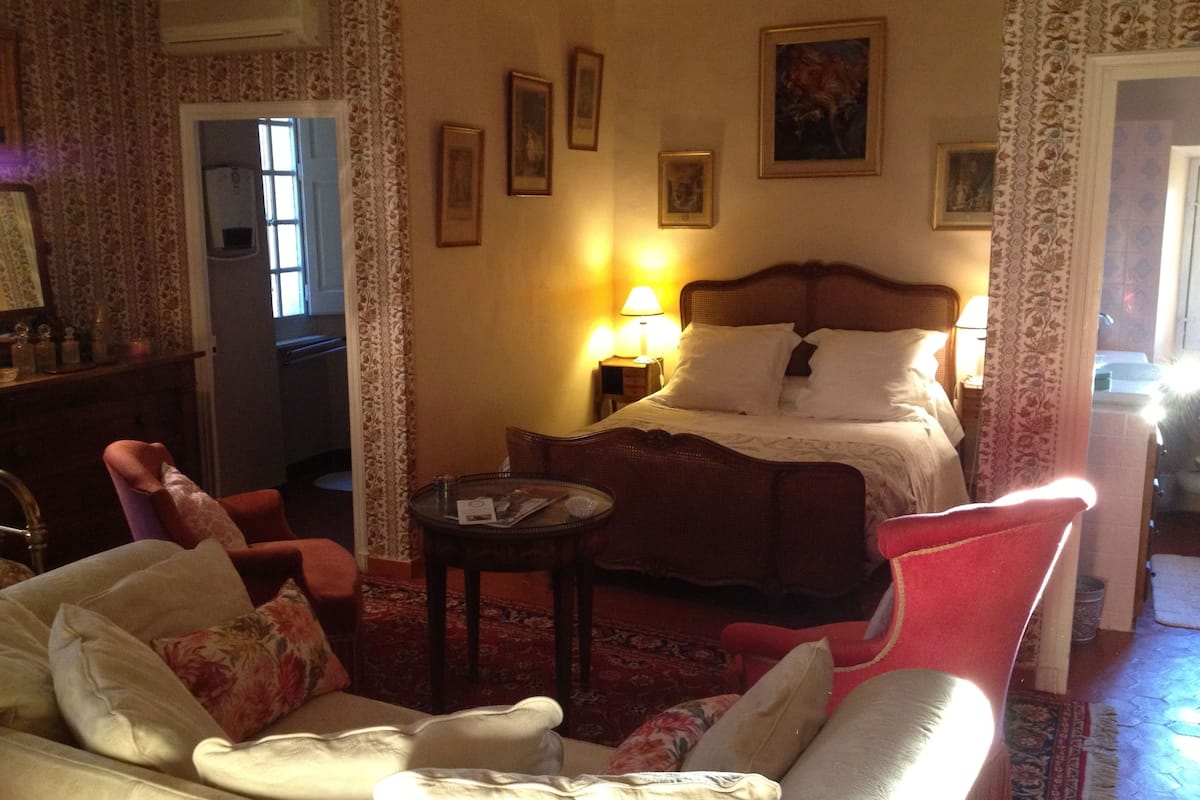 Ein Hotelzimmer mit Bett, einer Sitzecke mit Sofa und Sesseln, einem kleinen Tisch und einem Fenster.