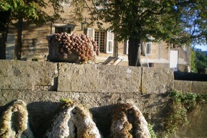 Un muro di pietra con una grande formazione rocciosa ricoperta di muschio in primo piano.