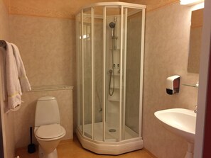 Ein Badezimmer mit Duschkabine, Toilette, Waschbecken und Handtuchhalter.