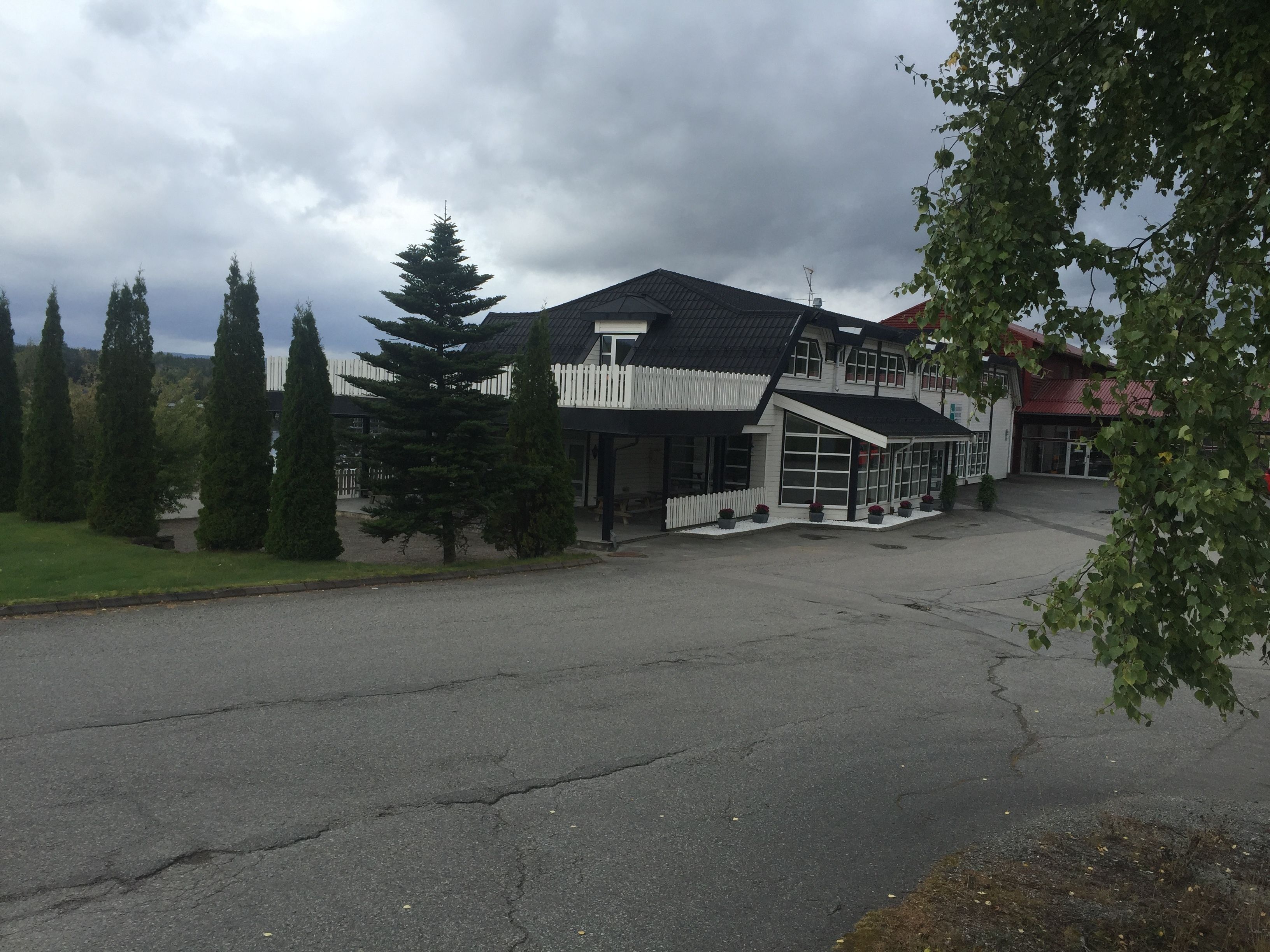 A two-story building with a white fence, large windows, and a sloped roof.
