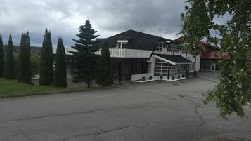 A two-story building with a white fence, large windows, and a sloped roof.