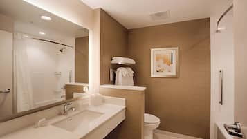 Un baño moderno con un espejo grande, un lavamanos, un inodoro y una zona de ducha.