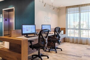 Un espacio de oficina moderno con tres estaciones de trabajo de computadora, un mostrador de recepción de madera y un ventanal con vistas a la ciudad.