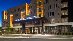 Un hotel moderno con una entrada destacada, varios pisos y una fachada bien iluminada.