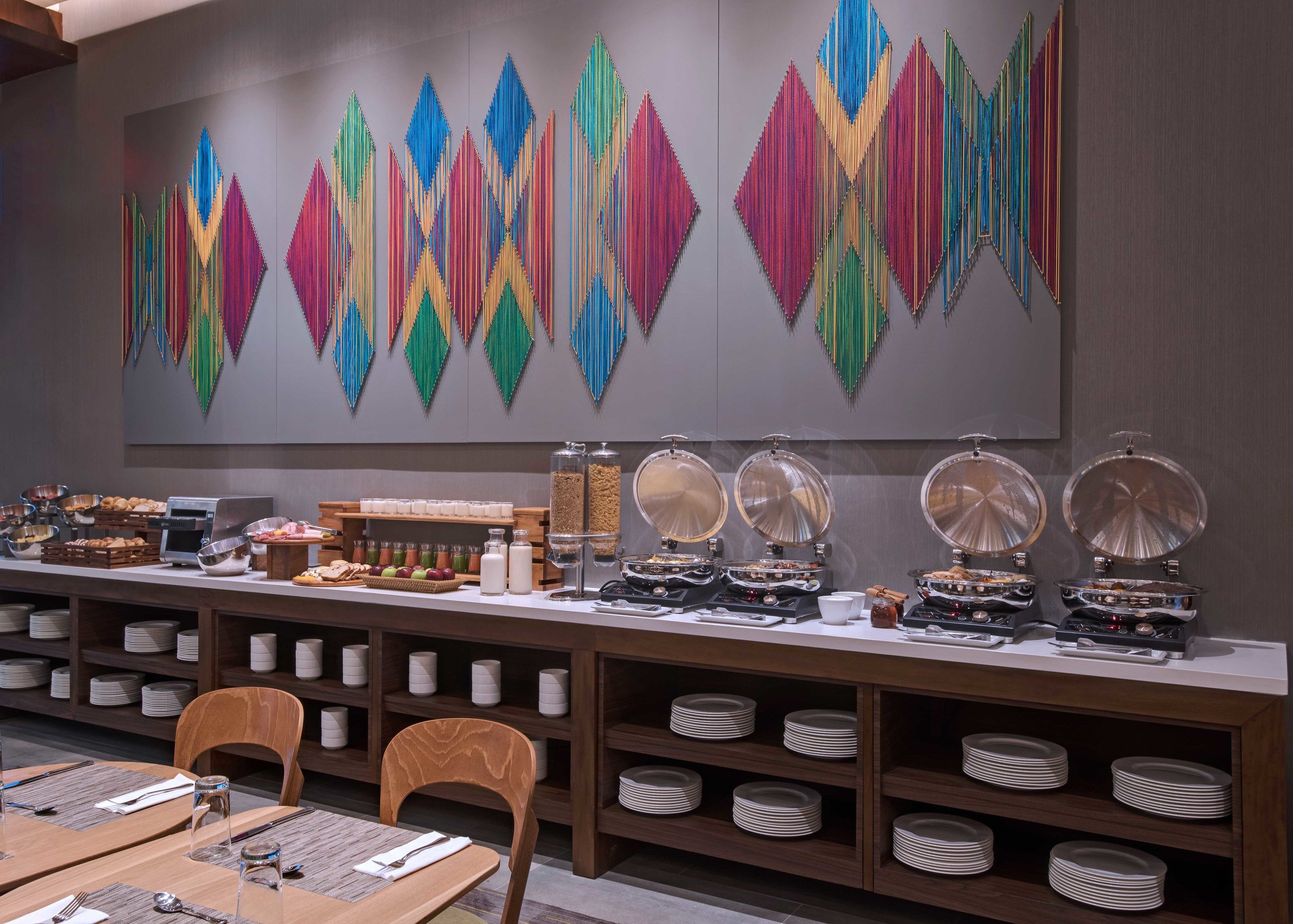 A buffet setup with various food items and a large decorative wall piece.