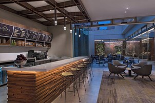 Un área de bar moderna con mostrador de madera, taburetes y una pizarra de menú.