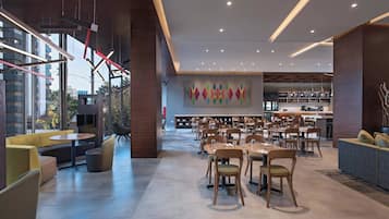 A modern dining area with tables and chairs, a bar area, and a seating area with sofas and a small table.