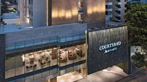 Un hotel moderno con un patio interior visible, que ofrece espacios de descanso y un gran letrero iluminado que dice "COURTYARD MARRIOTT".