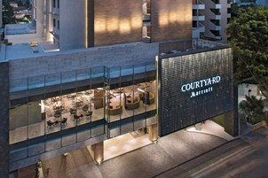Un hotel moderno con un patio interior visible, que ofrece espacios de descanso y un gran letrero iluminado que dice "COURTYARD MARRIOTT".