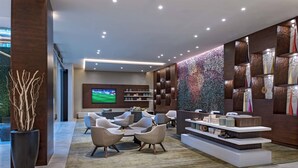 Un lobby moderno con una zona de estar, un televisor y una pared decorativa.