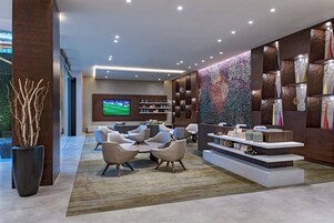 Un lobby moderno con una zona de estar, un televisor y una pared decorativa.