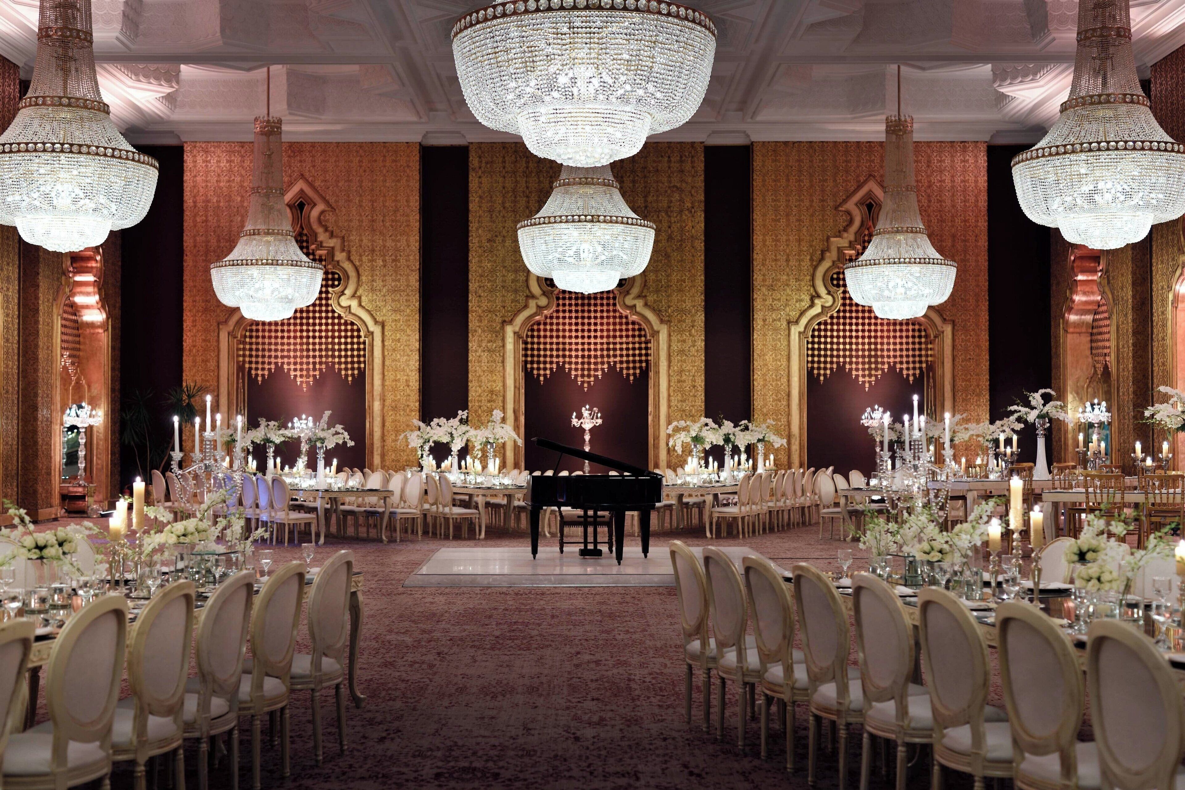 Un salón de baile imponente con candelabros, un piano de cola y mesas elegantemente dispuestas.