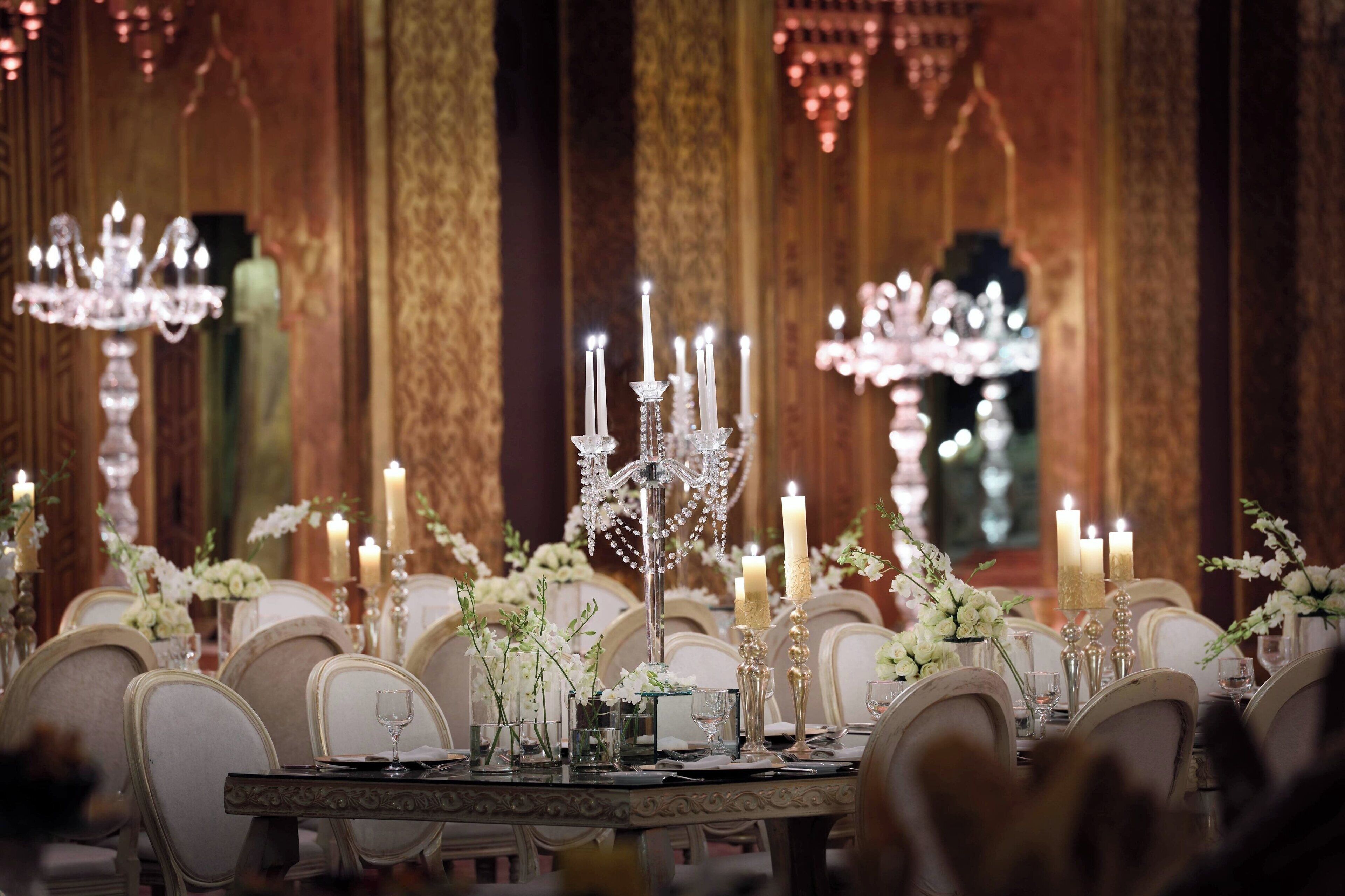 Een elegante eettafelsetting met kroonluchters, kaarsen en bloemdecoraties.