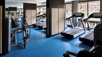 Un gimnasio con cintas de correr, elípticas y equipo de pesas.