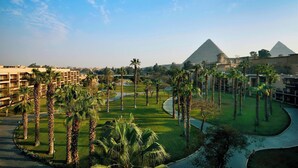 A resort with a view of the pyramids, palm trees, and a well-maintained lawn. - Marriott Mena House Cairo (Giza)