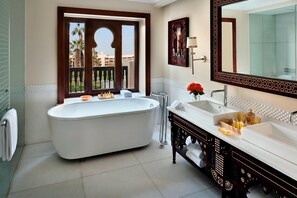 A bathroom with a freestanding bathtub, a double sink vanity, and a large mirror.