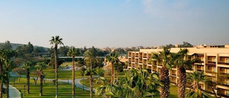 A hotel with a well-maintained lawn, palm trees, and a clear view of the surrounding area.