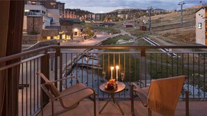 A balcony with two chairs and a small table, overlooking a train track and a town. - Heavenly Peak 310 4 BedroomCondo By Moving Mountains (Steamboat Springs)
