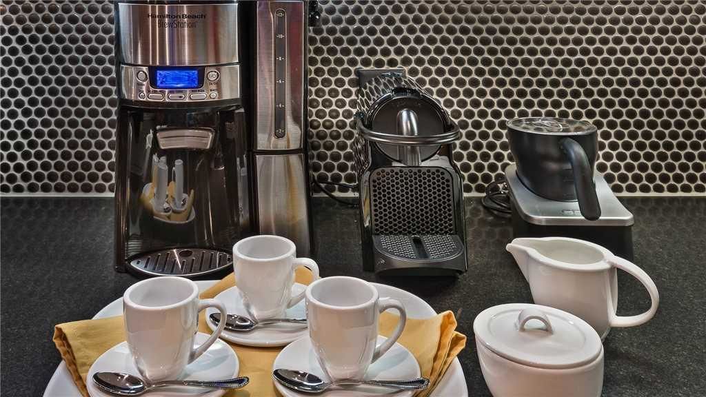 Une cuisine équipée d’une machine à café, d’un extracteur de jus, d’une bouilloire et d’une théière.