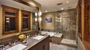 A modern bathroom with two sinks, a large mirror, and a glass shower enclosure. - Zen Mountain 311 3 BedroomCondo By Moving Mountains (Steamboat Springs)