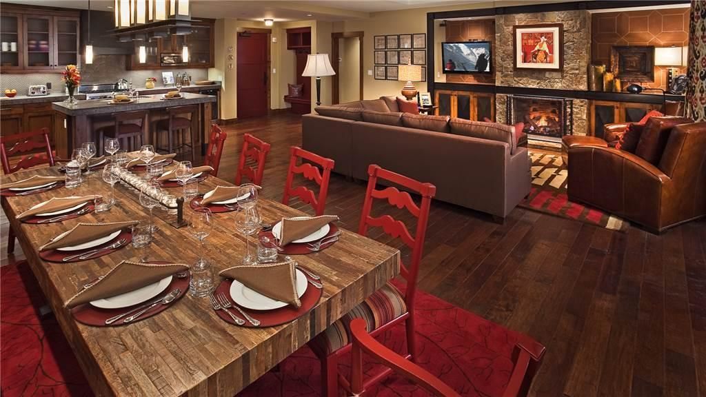 A spacious living area with a large wooden dining table set for a meal, a comfortable sofa, and a fireplace.