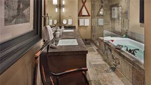 A modern bathroom with a marble countertop, two sinks, a large bathtub, and a glass-enclosed shower. - Hahns Peak 417 4 BedroomCondo By Moving Mountains (Steamboat Springs)
