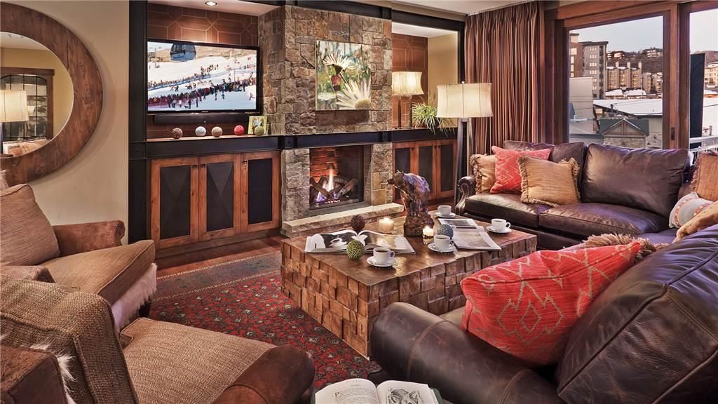 A cozy living room with a fireplace, leather sofas, a coffee table, and a television.