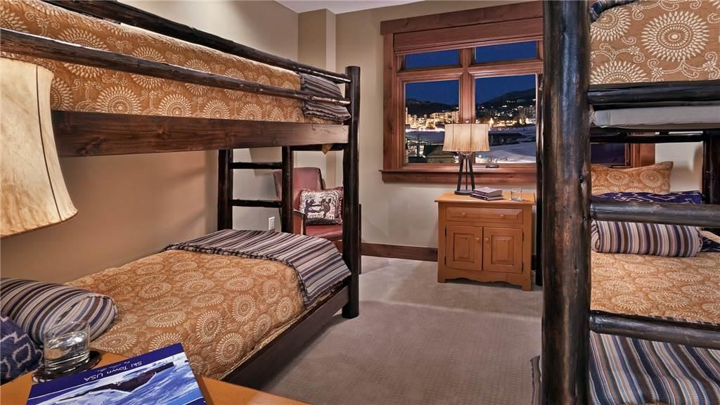 A bunk bed room with a city view, a wooden desk, and a chair.