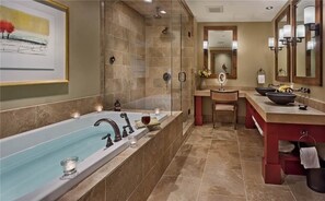 Ein geräumiges Badezimmer mit einer großen Badewanne, einer separaten Duschkabine, einem Waschtisch mit Spüle und einer großen Schüssel sowie einem Spiegel mit Wandleuchten.