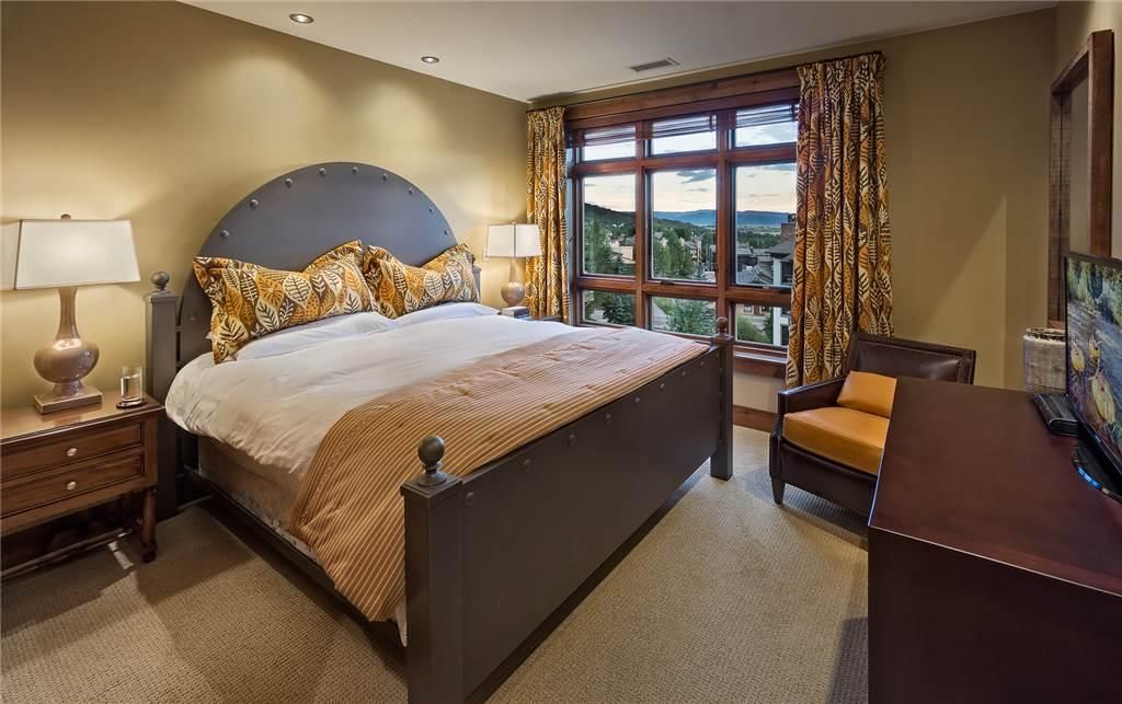 A hotel room with a large bed, a desk, and a view of the outdoors.