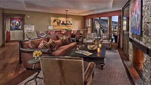 A spacious living room with a leather sofa, armchairs, a coffee table, and a fireplace. - Cougar Mountain 501 4 BedroomCondo By Moving Mountains (Steamboat Springs)