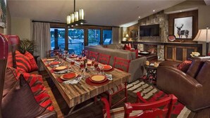 Un coin repas avec une table en bois dressée pour le repas, un canapé et une cheminée.