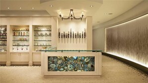 Un intérieur moderne avec une vitrine centrale, des étagères présentant divers objets et un mur décoratif agrémenté d’éléments verticaux.