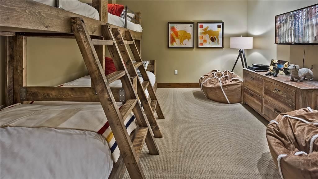 Een slaapkamer met een stapelbed, een bureau, een lamp en een televisie.